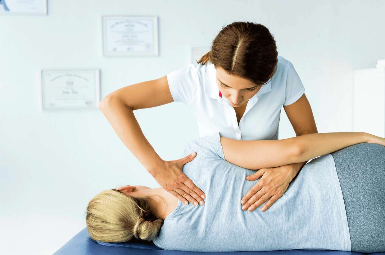img A woman receives a chiropractic adjustment on her back from a healthcare professional in a clinical setting.